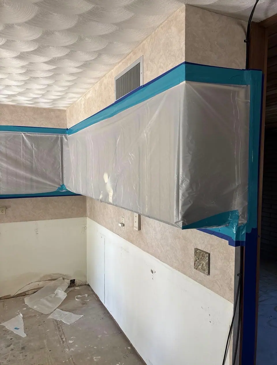 Kitchen cabinets sealed behind plastic sheeting and tape before mold work starts