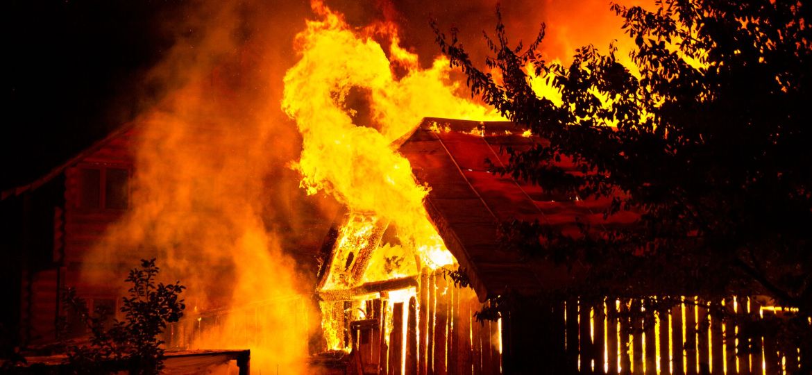Wooden house or barn burning on fire at night.